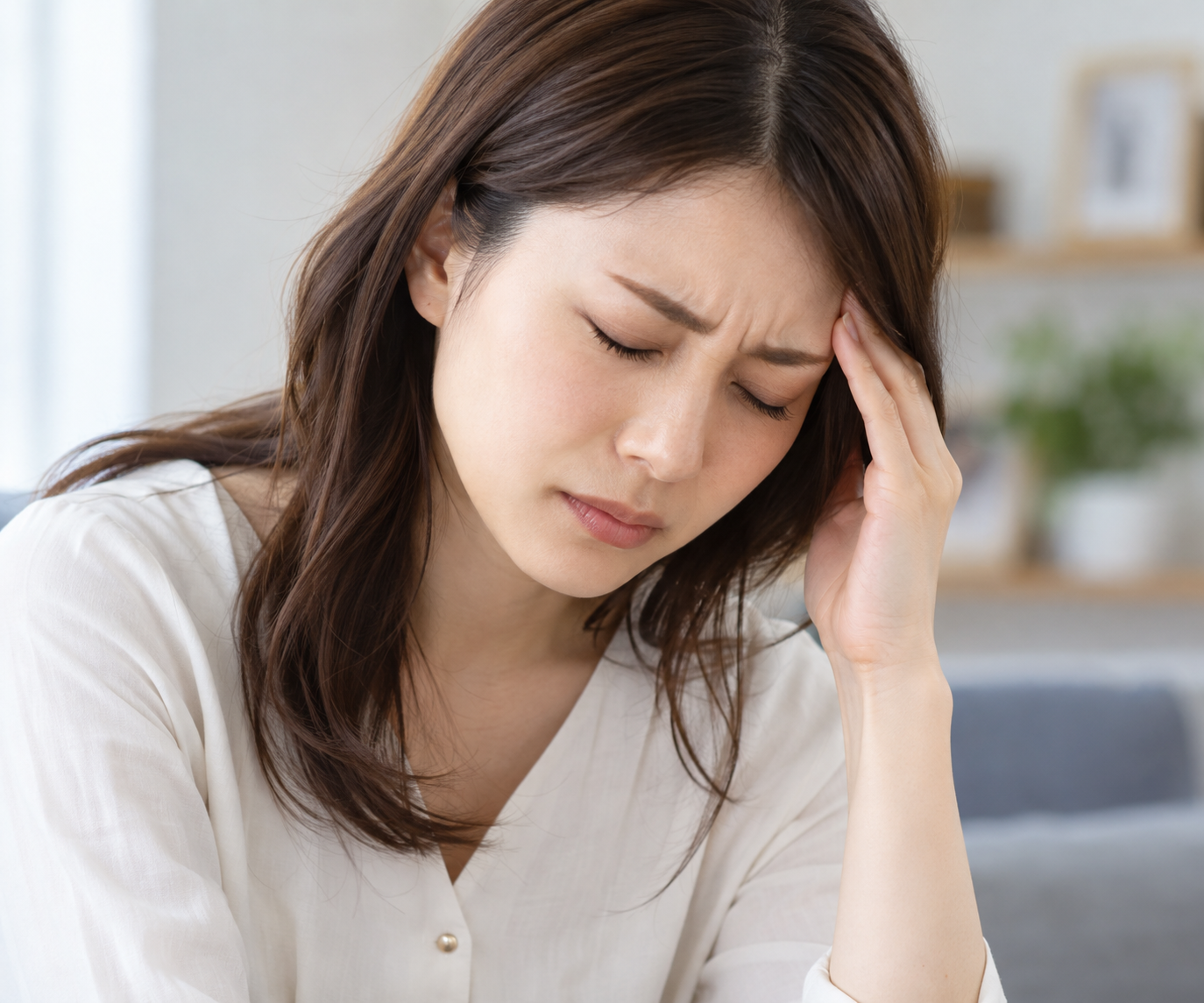デスクワークによって慢性的な頭痛に悩む30代女性のイメージ